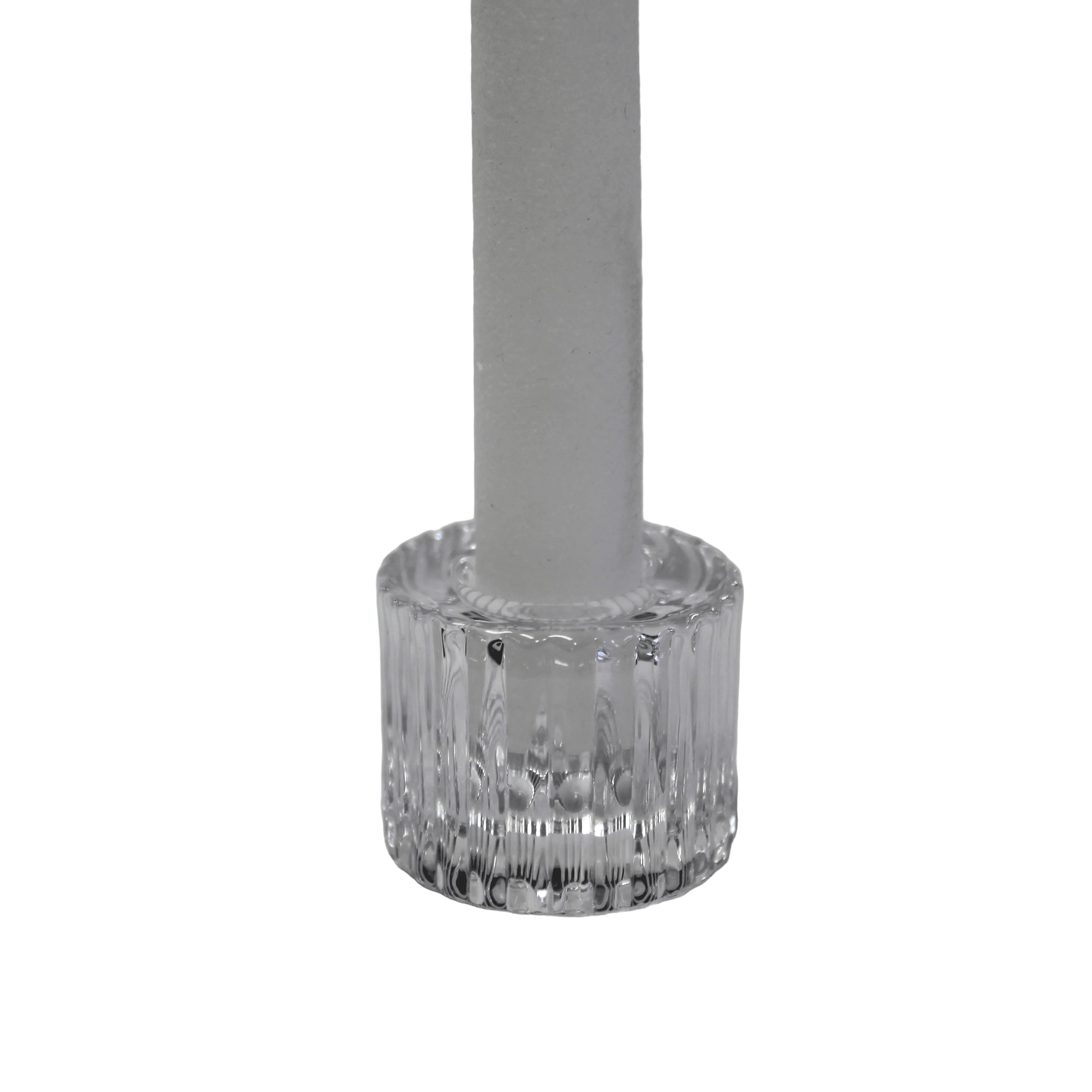 A clear ribbed glass candle holder base holding a white taper candle, set against a soft, light gray fabric background.