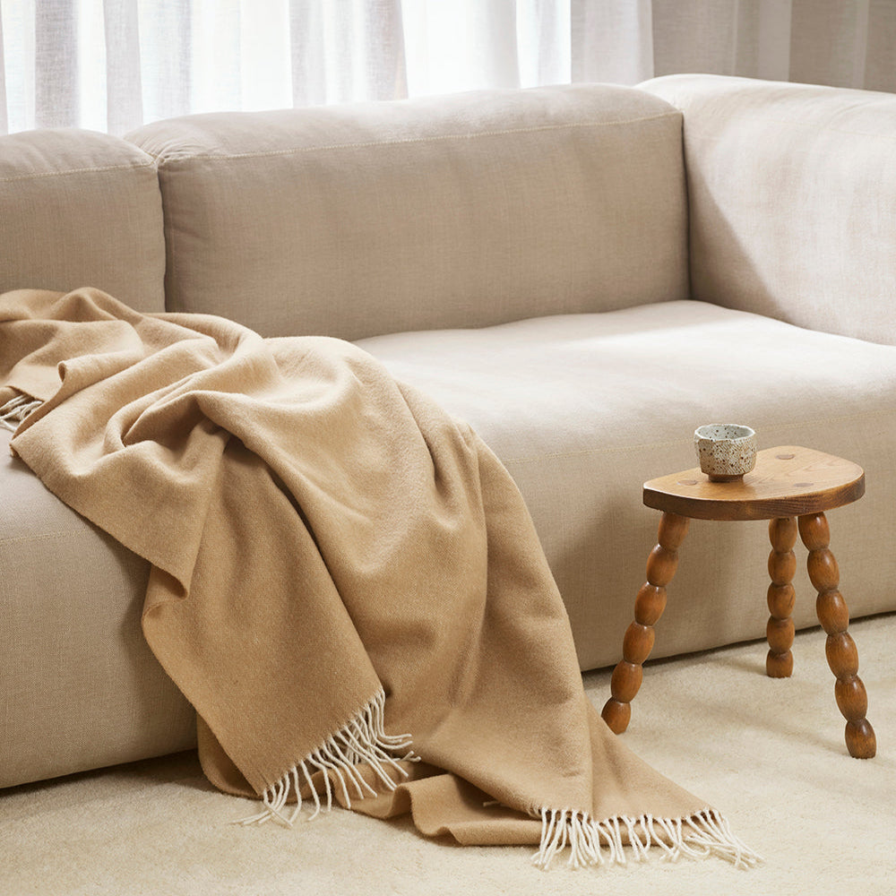 Merino wool blanket throw by Baya in Sand shade on sofa